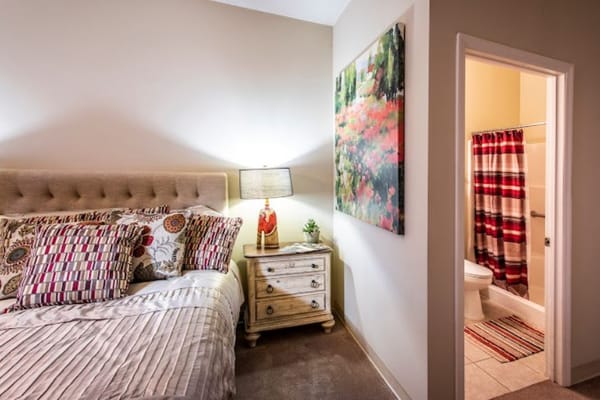 Brightly decorated bedroom with a bed, side table, and a bathroom entrance