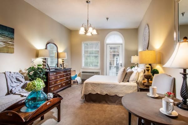A cozy living room featuring a bed, dresser, and comfortable seating.
