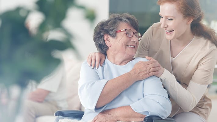 Resident smiling with a staff member in an interior setting
