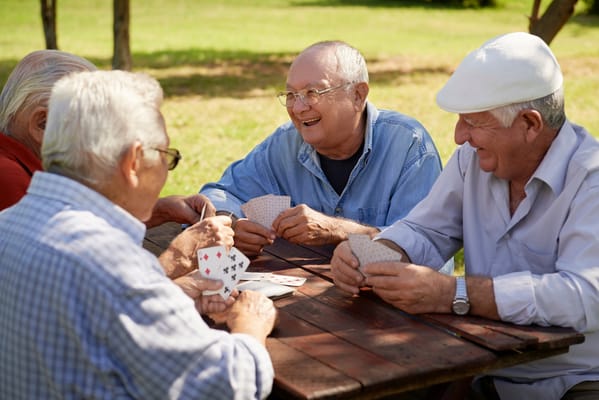 Seniors playing cards in an outdoor setting