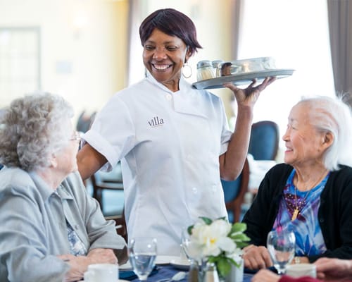 Staff serving food to residents in a dining area