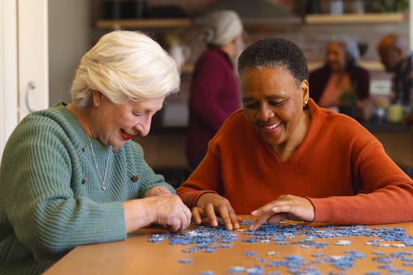 Two residents enjoying a puzzle together indoors