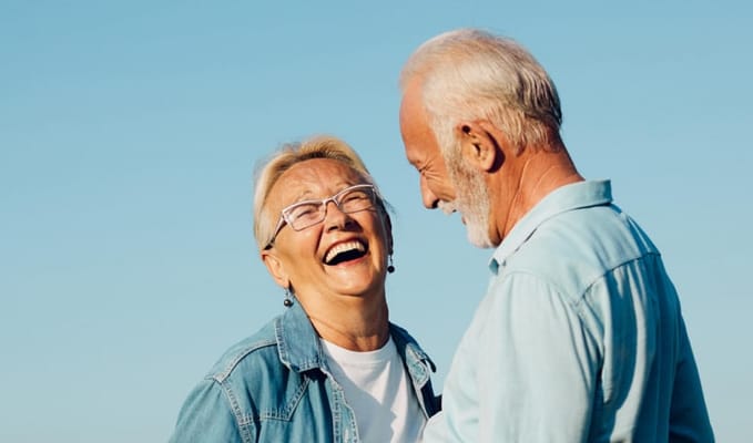 Two elderly individuals laughing together outdoors