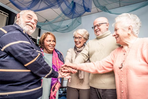 Group of residents smiling and holding hands in a common area