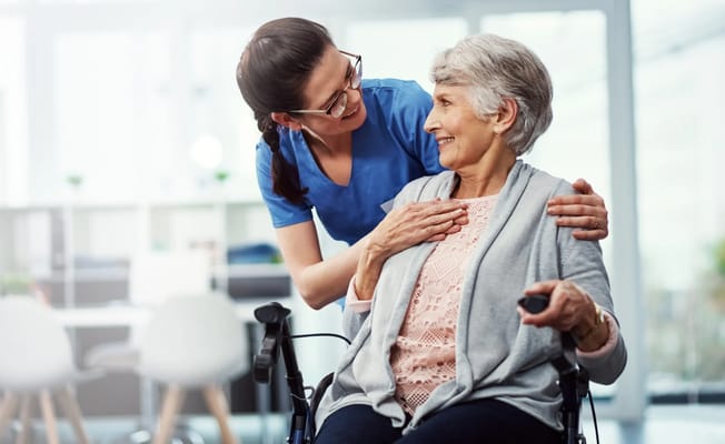 Staff member assisting a smiling resident in a care setting