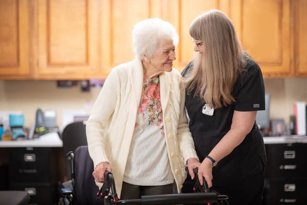 Care staff assisting a resident in a cozy interior setting