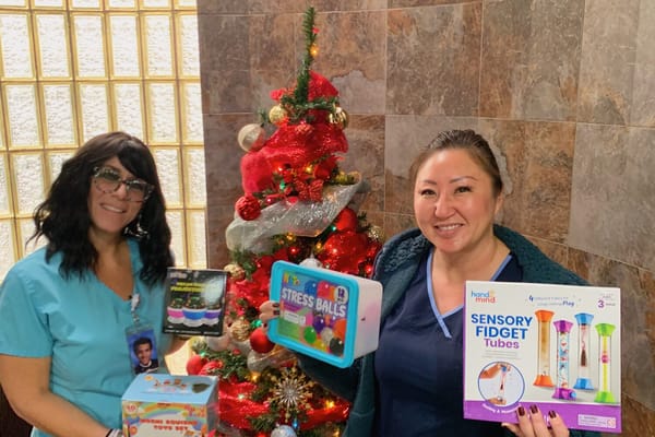 Staff members with sensory toys near a Christmas tree