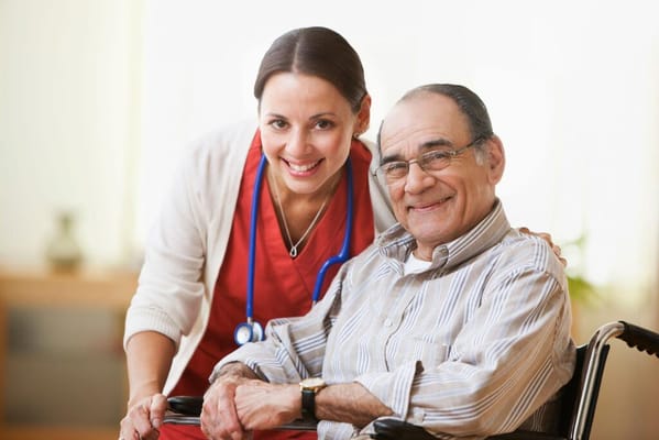 A nurse smiling with a resident in a wheelchair