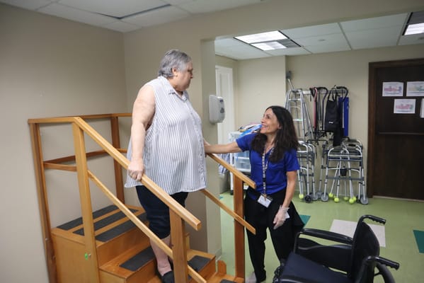 Staff assisting a resident on stairs in an activity area