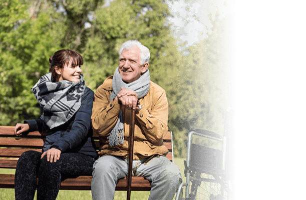 Senior man and caregiver sitting together on a park bench