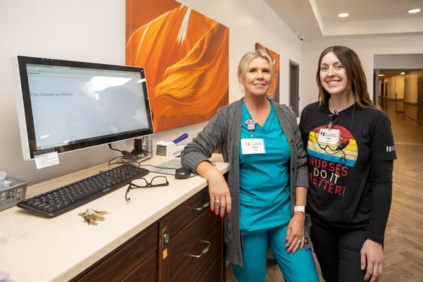 Two staff members posing in a facility hallway