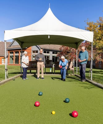 Residents playing bocce ball under a tent
