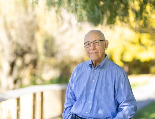 Senior man smiling outdoors in a park-like setting