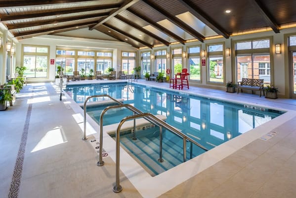 Indoor swimming pool with natural light and seating area
