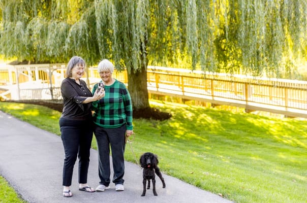 Two residents enjoying a walk in the garden with a dog