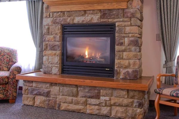 Stone fireplace with a fire in a lounge area