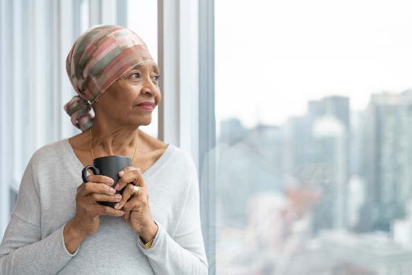 A woman holding a cup while looking outside a large window