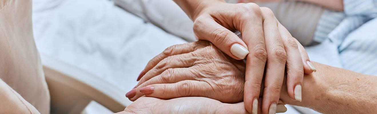 Two hands comforting an elderly person's hands