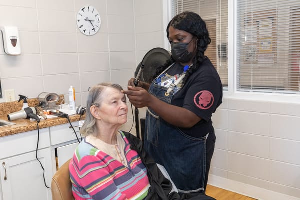 Staff member styling a resident's hair in a salon area