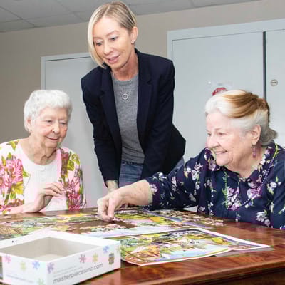 Residents engaging in a puzzle activity with staff assistance