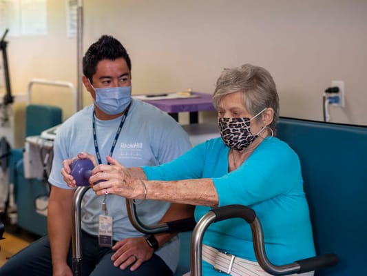 A staff member assisting a resident with therapy exercises