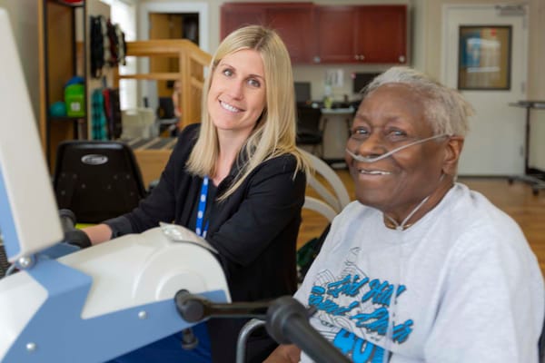 Staff assisting a resident with therapy equipment