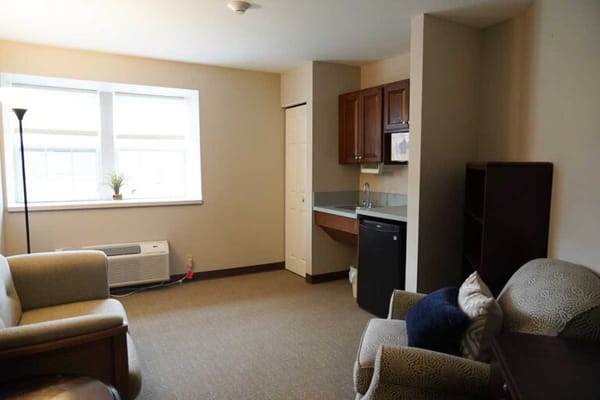 A cozy resident room with seating and kitchenette
