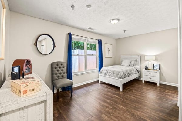 Brightly lit resident bedroom with furnishings