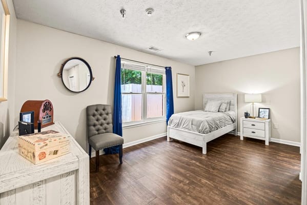 Brightly lit resident bedroom with furnishings