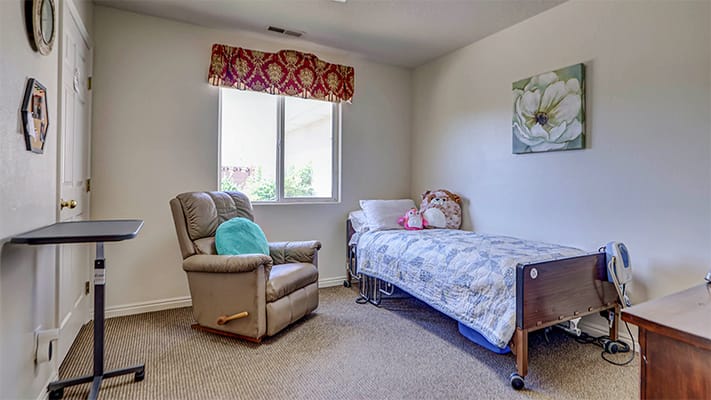 Cozy private resident room with a chair and bed