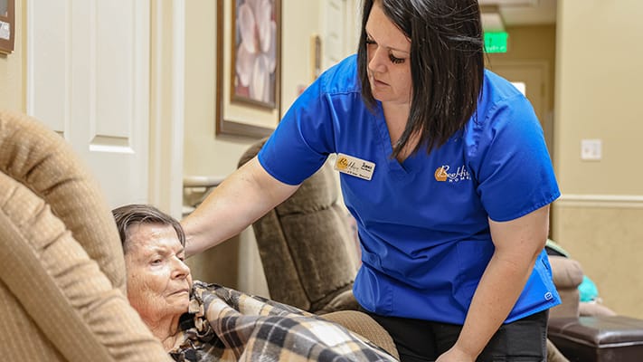 Care staff assisting a resident in a cozy sitting area