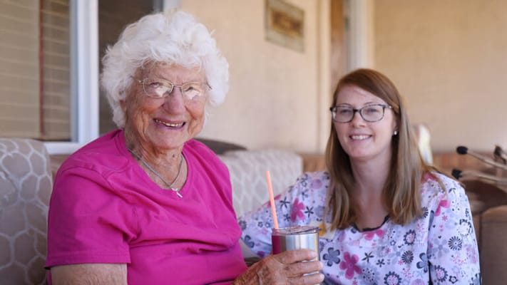 Resident and staff member smiling together on a patio