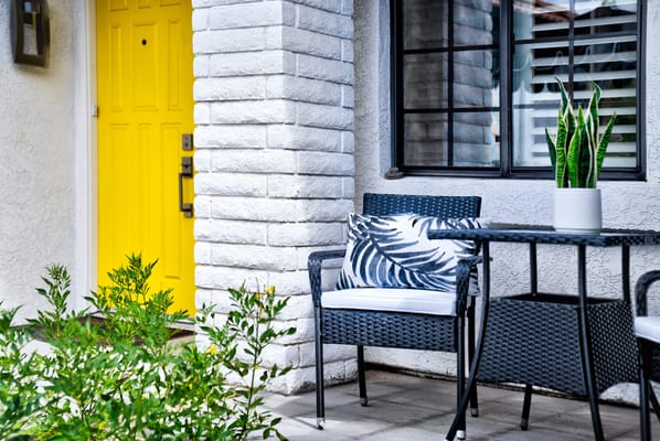 Bright outdoor seating area with a yellow door