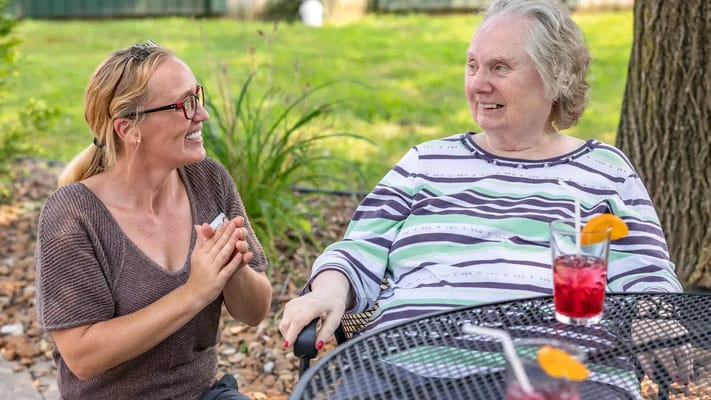 A resident chatting with staff outdoors, enjoying drinks