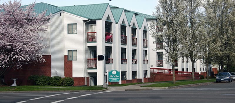 Exterior view of Elms Retirement Center with blooming trees