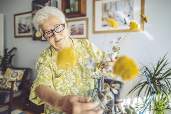 Elderly woman arranging flowers in a bright common area