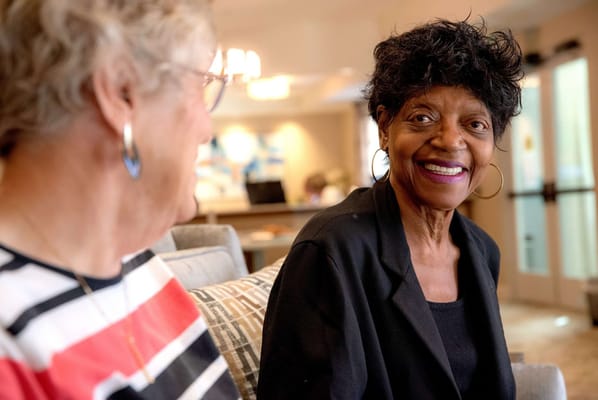 Two residents smiling and chatting in a common area