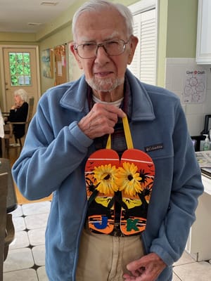 Resident proudly holding decorated flip-flops