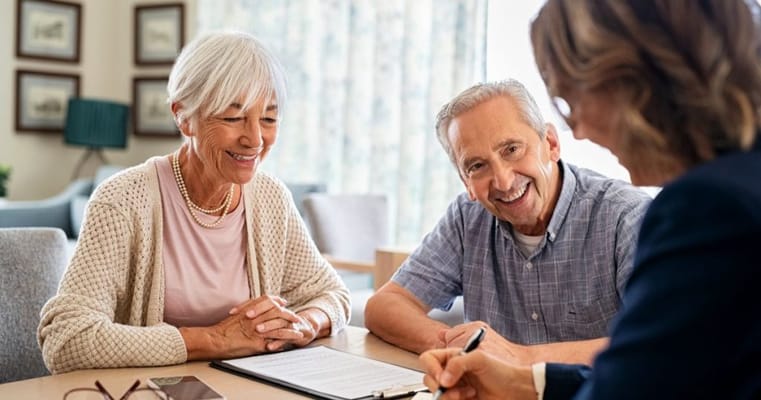 Two seniors engaging with a staff member at a table