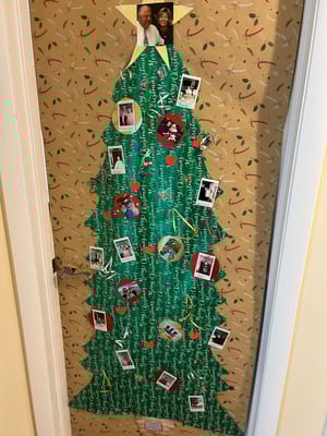 Decorated door resembling a Christmas tree with photos and ornaments