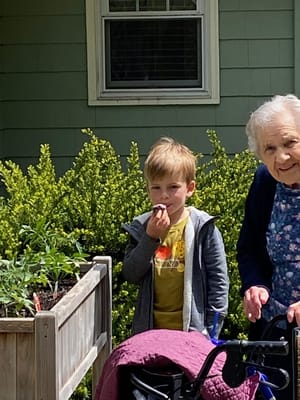 An elderly woman assisting a child in a garden
