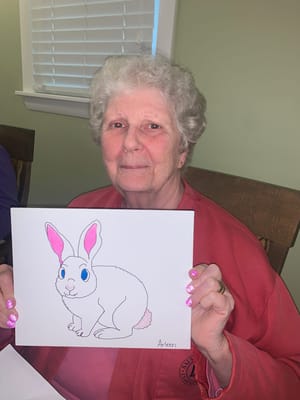 Elderly woman holding a colorful drawing of a bunny