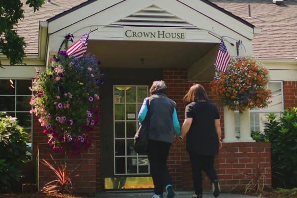 Two women walk towards a senior living facility entrance