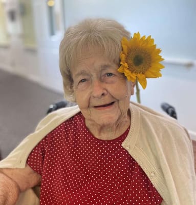 A resident smiling with a sunflower in her hair