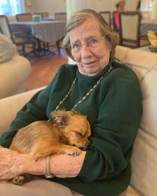 Resident holding a small dog in a cozy setting