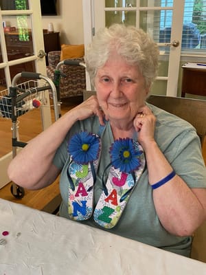 Resident showing decorated flip-flops in activity room