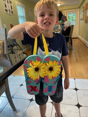A child holding a decorated craft in a common area