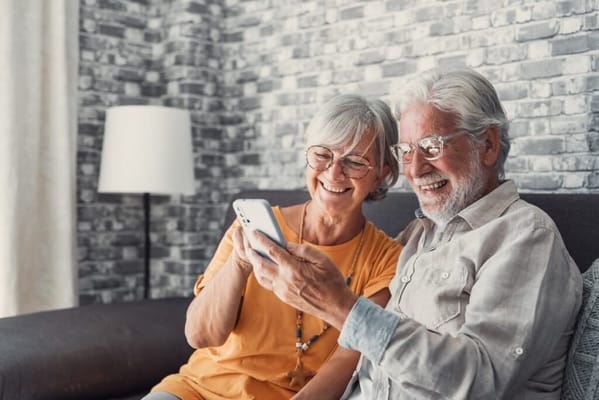 Senior couple smiling while looking at a phone