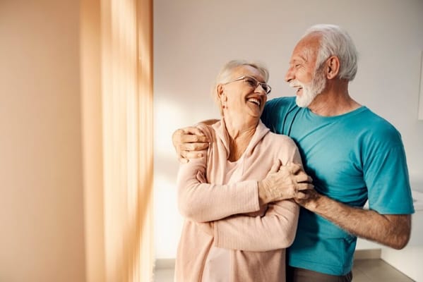 Elderly couple smiling and embracing indoors
