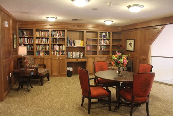 Library area with bookshelves, seating, and a round table